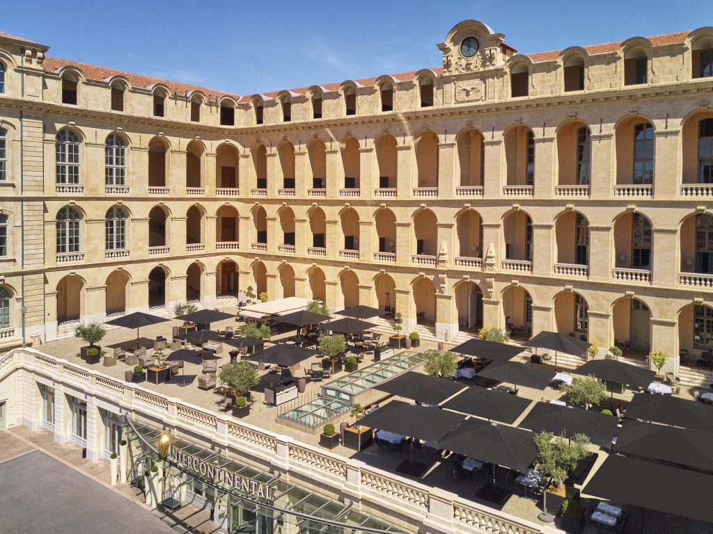 Terrasse panoramique de l'InterContinental Marseille Hôtel-Dieu en été, tables dressées sous les parasols face à la façade classée Monument Historique © Eric Cuvillier